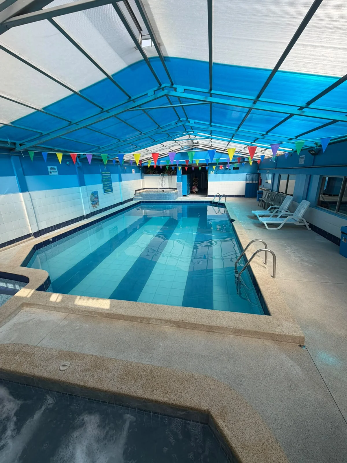 Piscina temperada con área de descanso y asoleadoras